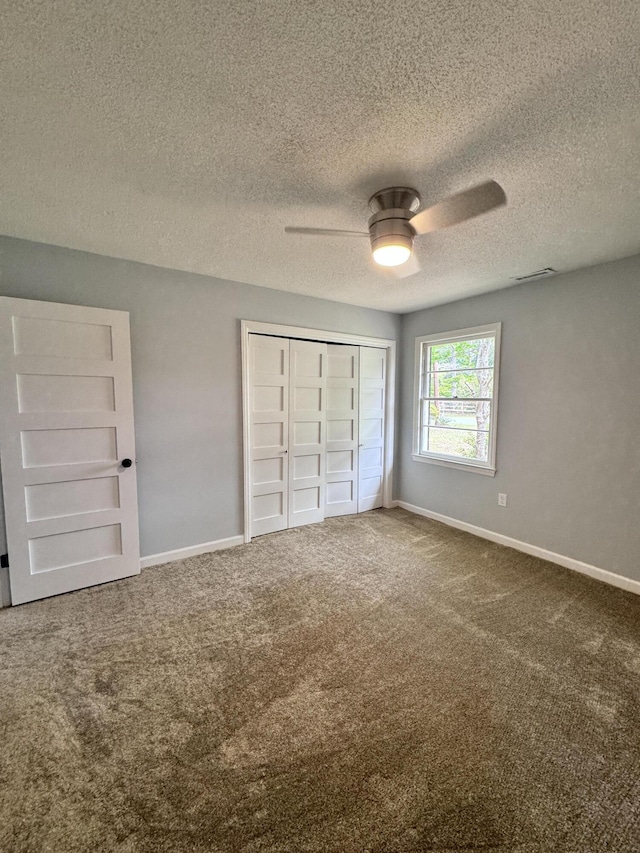 unfurnished bedroom featuring ceiling fan, carpet flooring, a closet, and a textured ceiling