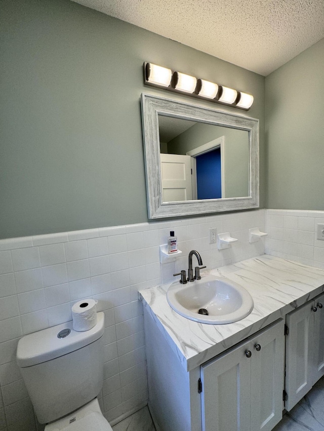 bathroom featuring vanity, tile walls, a textured ceiling, and toilet