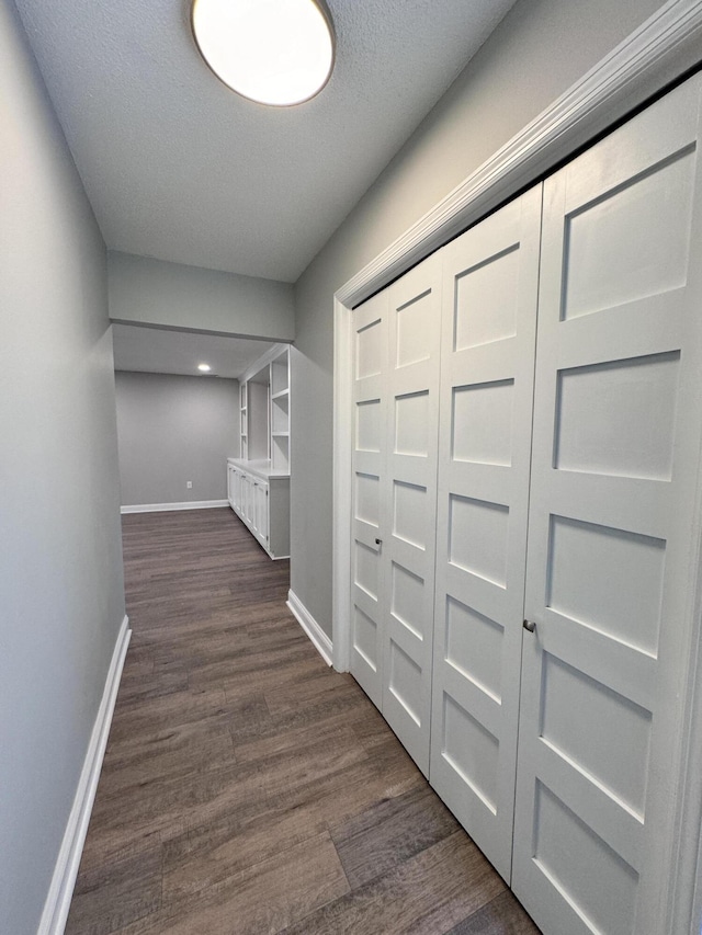 corridor with a textured ceiling and dark hardwood / wood-style flooring