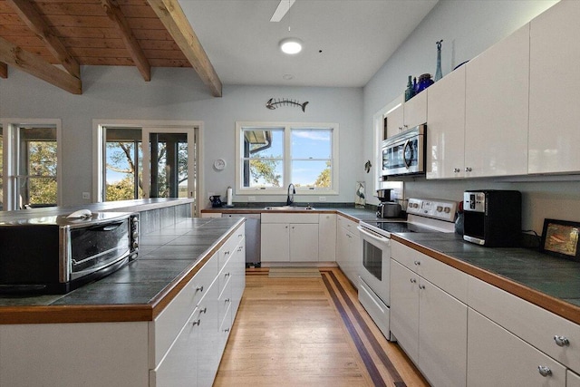 kitchen featuring beamed ceiling, light hardwood / wood-style flooring, appliances with stainless steel finishes, white cabinetry, and sink