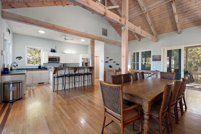 dining area featuring light hardwood / wood-style flooring, a healthy amount of sunlight, and high vaulted ceiling