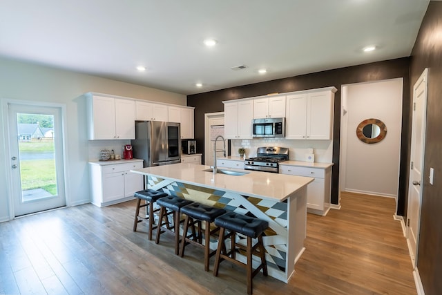 kitchen with stainless steel appliances, a sink, tasteful backsplash, a kitchen breakfast bar, and light countertops