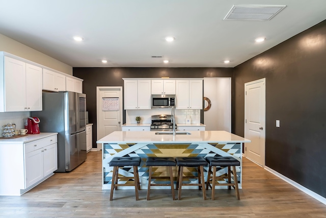 kitchen featuring stainless steel appliances, light countertops, a breakfast bar, white cabinetry, and recessed lighting