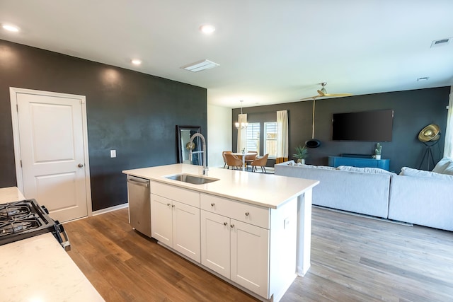 kitchen featuring stainless steel dishwasher, wood finished floors, white cabinets, open floor plan, and recessed lighting