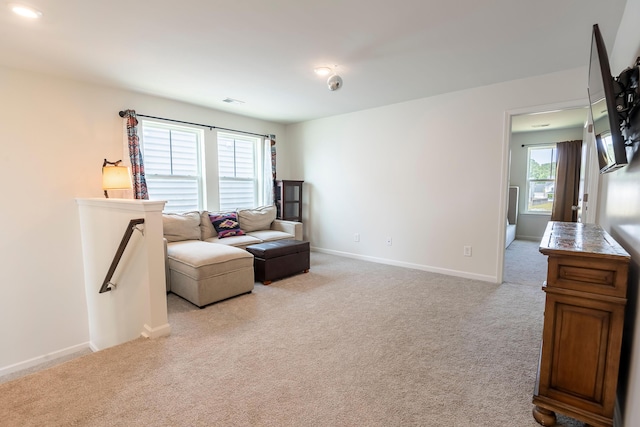 living area featuring light carpet and baseboards