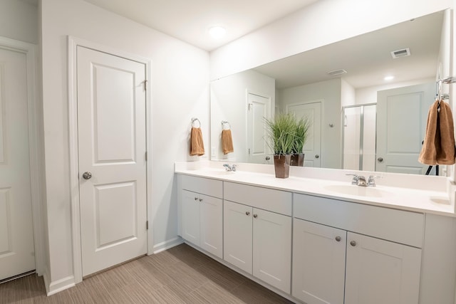 full bath featuring a shower stall, double vanity, baseboards, and recessed lighting