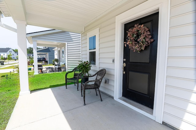 doorway to property with a porch and a yard