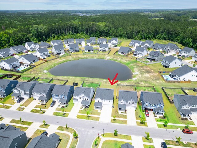 aerial perspective of suburban area with a nearby body of water and a heavily wooded area