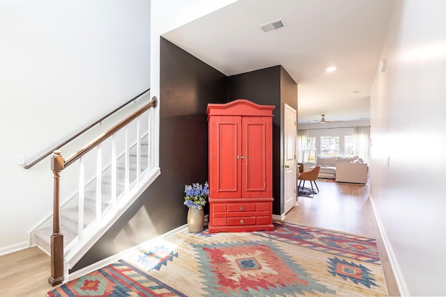stairs featuring wood finished floors, baseboards, and ceiling fan
