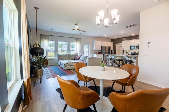 dining space featuring wood finished floors, a chandelier, baseboards, recessed lighting, and a ceiling fan