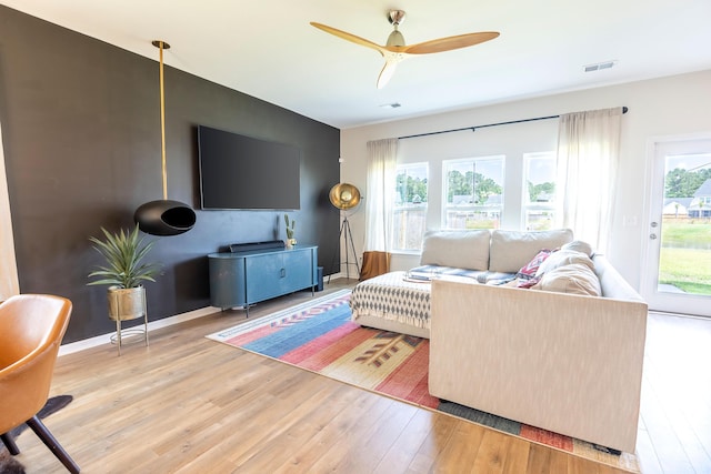 living area featuring light wood finished floors, a ceiling fan, and baseboards