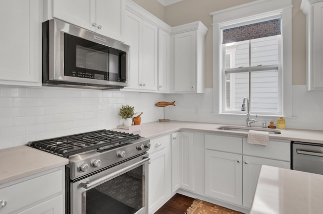 kitchen featuring appliances with stainless steel finishes, decorative backsplash, white cabinets, and sink