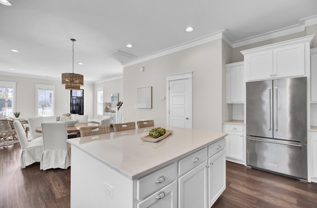 kitchen featuring high end refrigerator, hanging light fixtures, ornamental molding, white cabinets, and a center island