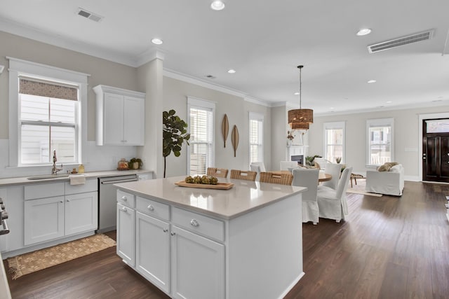 kitchen with sink, dishwasher, hanging light fixtures, white cabinets, and a center island