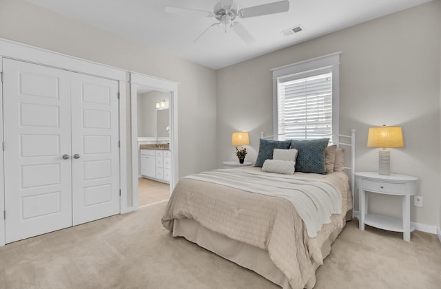 carpeted bedroom featuring ceiling fan, ensuite bathroom, and a closet