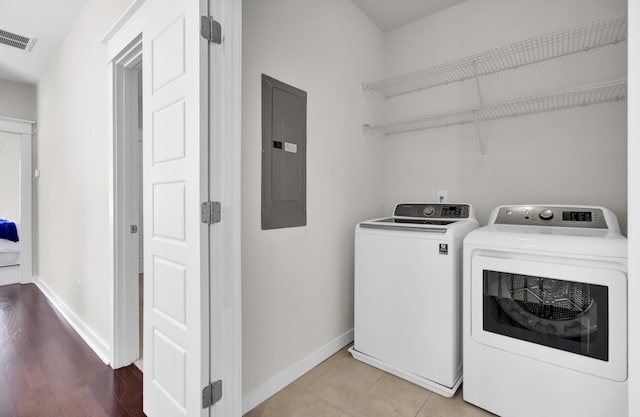 clothes washing area with washing machine and dryer, light tile patterned floors, and electric panel