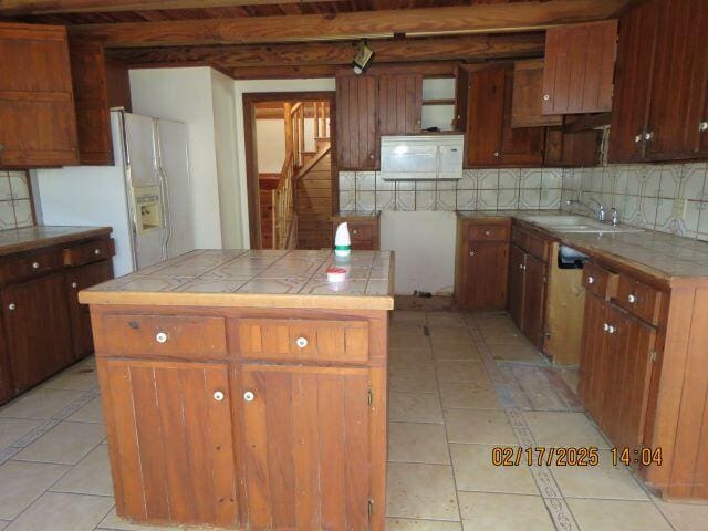 kitchen with tile counters, a kitchen island, sink, tasteful backsplash, and light tile patterned floors