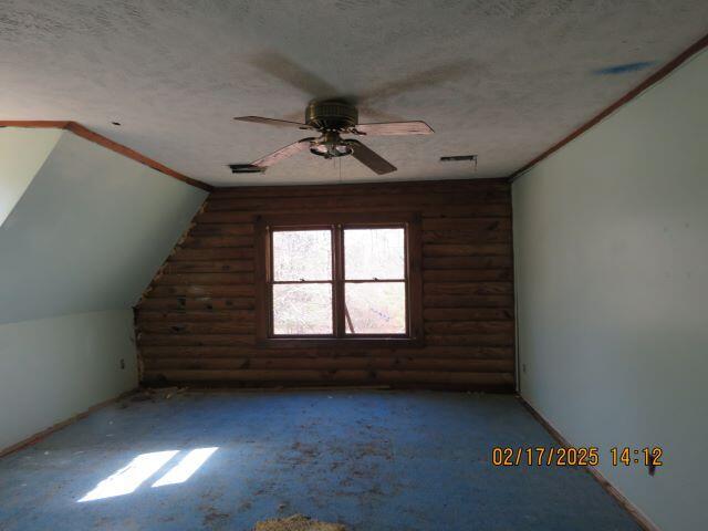 bonus room with a textured ceiling, lofted ceiling, log walls, and ceiling fan