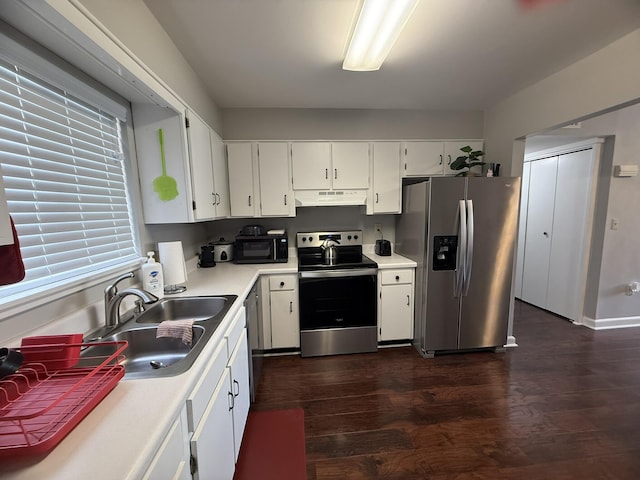 kitchen featuring a sink, appliances with stainless steel finishes, under cabinet range hood, and dark wood finished floors