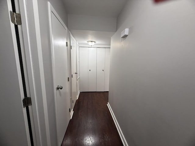 hallway with dark wood finished floors and baseboards