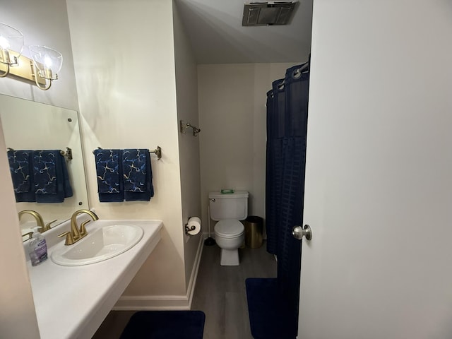 bathroom featuring a sink, visible vents, baseboards, toilet, and wood finished floors