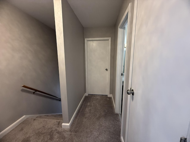 corridor with an upstairs landing, carpet flooring, and baseboards