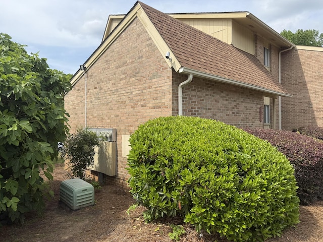 view of side of property featuring roof with shingles and brick siding