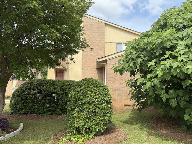 view of home's exterior with crawl space and brick siding