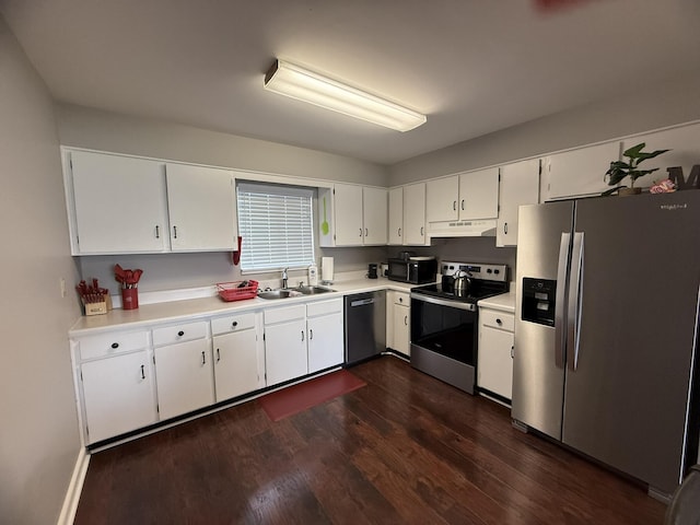 kitchen featuring under cabinet range hood, appliances with stainless steel finishes, white cabinets, a sink, and dark wood-type flooring