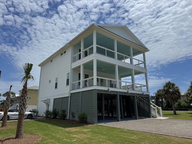 305 Matilda St, Edisto Beach, SC 29438 - back of property featuring board and batten siding, a balcony, stairway, gravel driveway, and a yard