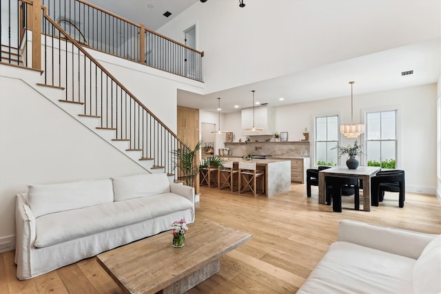 1474 Blue Cascade Dr, Mount Pleasant, SC 29464 - living room with light wood-style flooring, stairs, a chandelier, and a towering ceiling