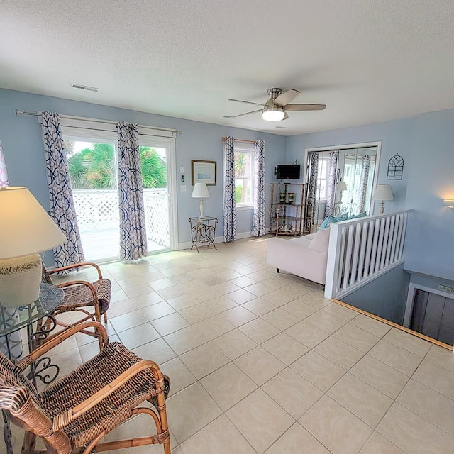 tiled living room with ceiling fan and a textured ceiling