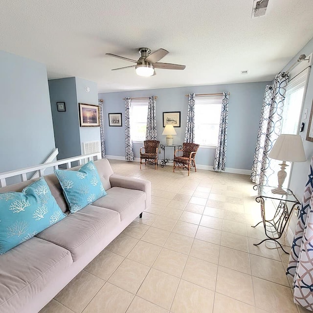 tiled living room featuring ceiling fan and a textured ceiling