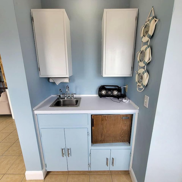 bar featuring white cabinetry, sink, and light tile patterned floors