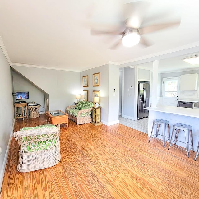 living room featuring crown molding, ceiling fan, and light wood-type flooring