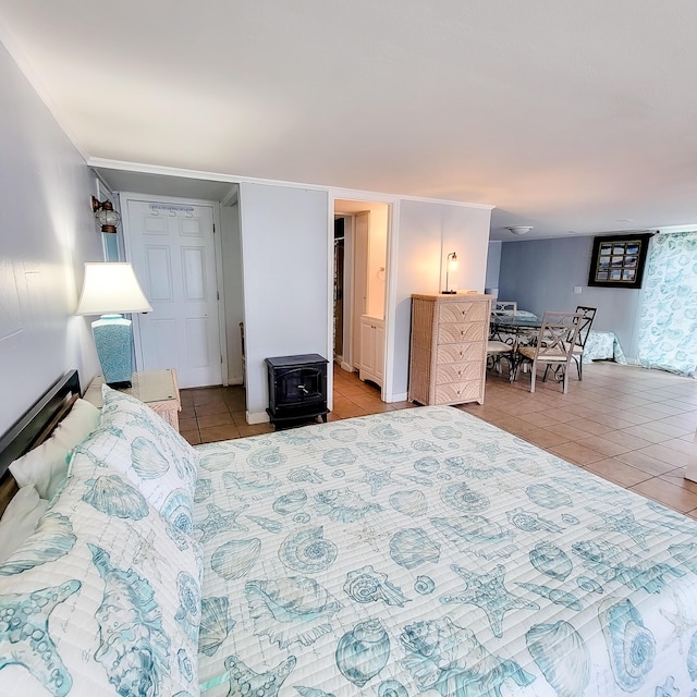 bedroom featuring light tile patterned floors and a wood stove