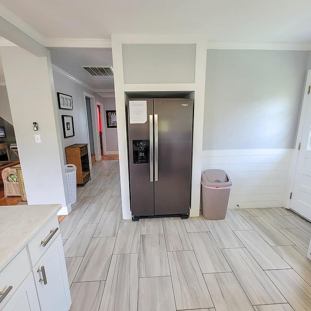 kitchen with crown molding, stainless steel fridge, and white cabinets