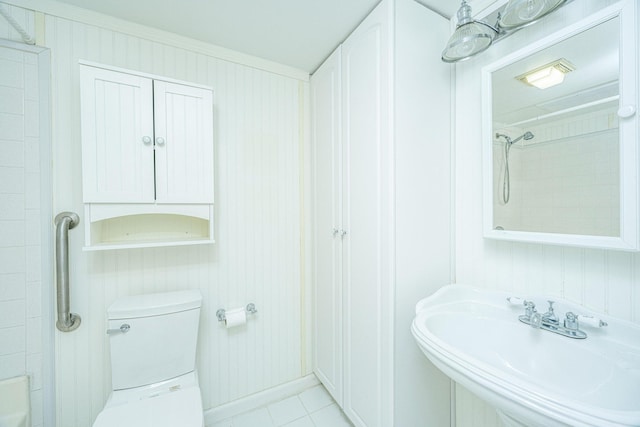 bathroom with tile patterned floors, sink, a tile shower, and toilet