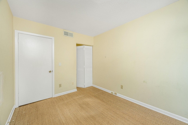 unfurnished bedroom featuring light colored carpet and a closet