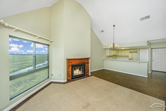 unfurnished living room featuring a water view, high vaulted ceiling, and a chandelier