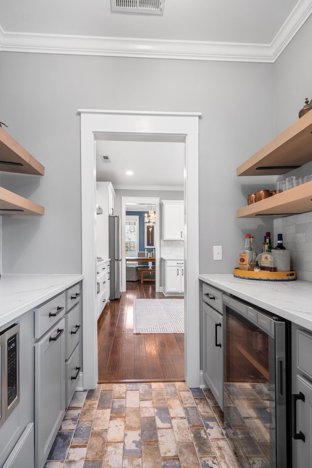 bar featuring beverage cooler, decorative backsplash, and ornamental molding