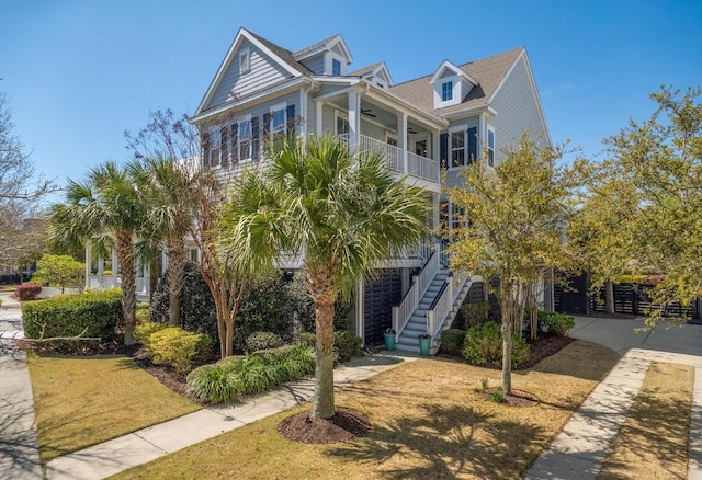 coastal inspired home with ceiling fan, a balcony, and stairway