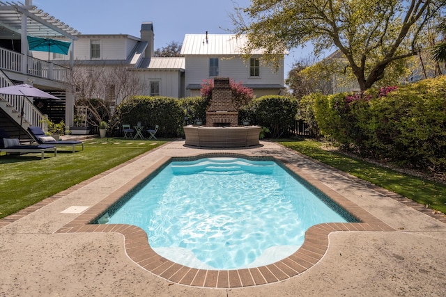 outdoor pool with a yard, a patio area, a brick fireplace, and stairway