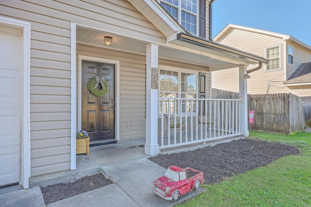 entrance to property featuring a garage, a porch, and fence