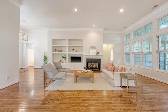 living room with baseboards, a fireplace with flush hearth, wood finished floors, visible vents, and ornamental molding