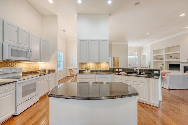 kitchen featuring white appliances, plenty of natural light, a sink, and light wood finished floors