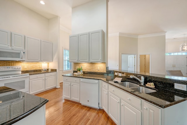kitchen featuring a sink, light wood finished floors, white appliances, and a wealth of natural light