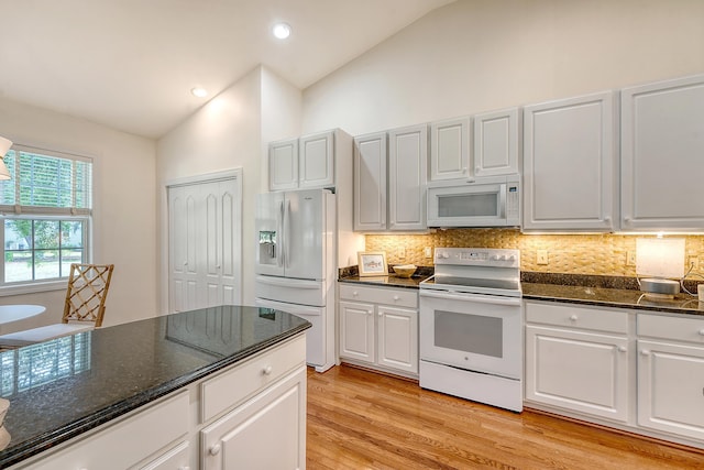 kitchen with decorative backsplash, vaulted ceiling, white appliances, and light wood-style flooring