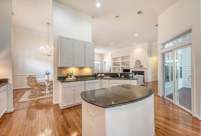kitchen featuring visible vents, ornamental molding, a peninsula, light wood-style floors, and dishwasher