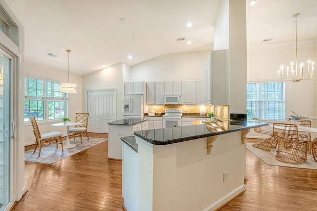 kitchen with visible vents, a kitchen island, white appliances, and light wood-type flooring